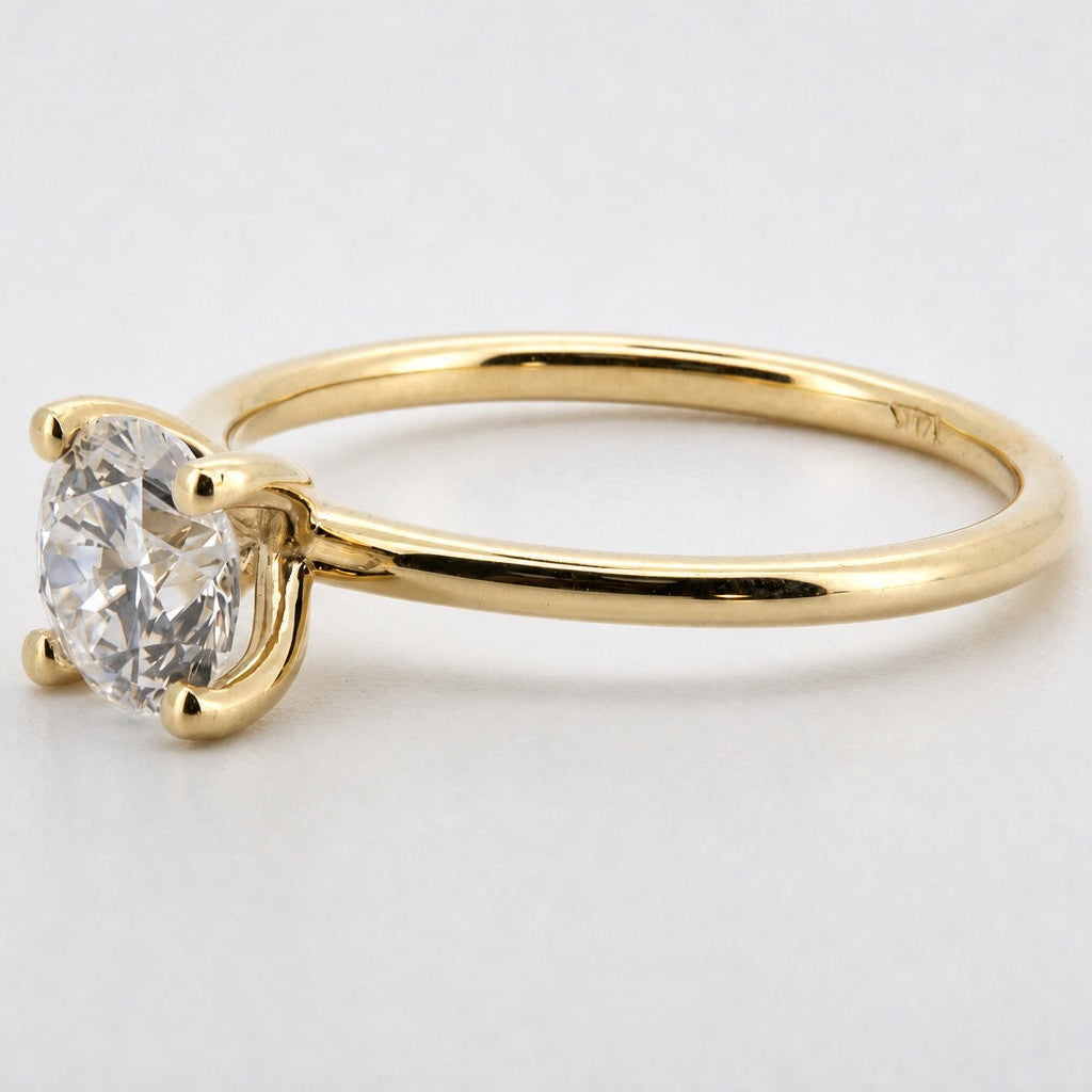 Three-quarter view of a round solitaire engagement ring in 14K yellow gold