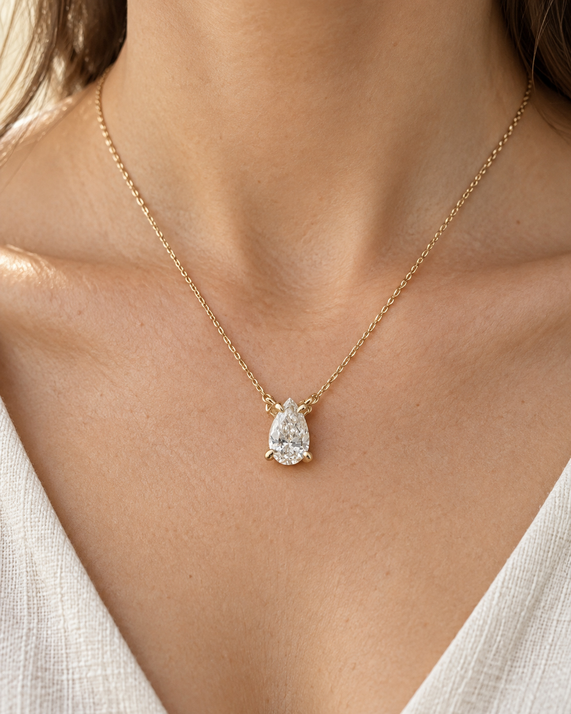 Yellow-gold pear solitaire necklace worn with the pendant facing forward — AI-generated wearing illustration. SKU 10051.